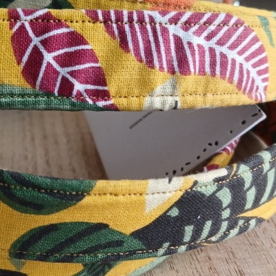 Faixa de tecido com padrão de folhas coloridas sobre fundo amarelo