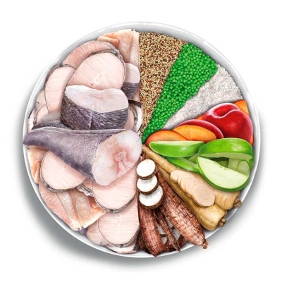 Tigela branca com peixe, grãos, legumes e fruta cortada em secções