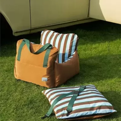 Almofadas para assento com riscas castanhas e brancas e alças verdes na relva