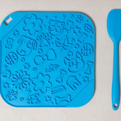 Utensílios de cozinha em silicone azul com tapete quadrado decorado e espátula.