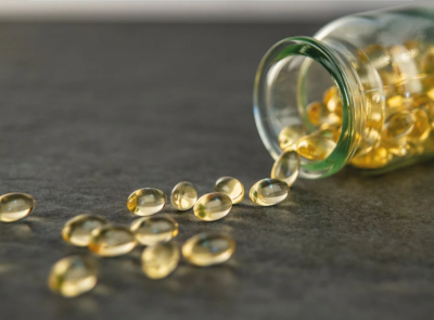 Frasco de vidro aberto com cápsulas amarelas espalhadas