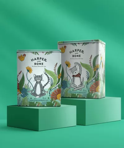 Duas latas metálicas decoradas com desenhos de gato e cão e flores, texto HARPER AND BONE, sobre bases verdes