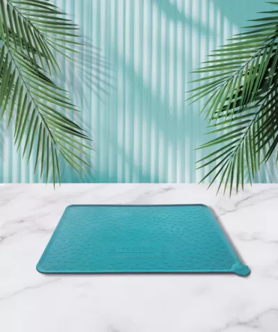 Tapete azul com textura de bolinhas colocado em superfície branca com padrão mármore e fundo azul com sombras de folhas de palmeira