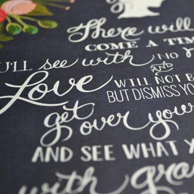 Tecido azul escuro com texto caligráfico branco e flores coloridas no canto superior esquerdo