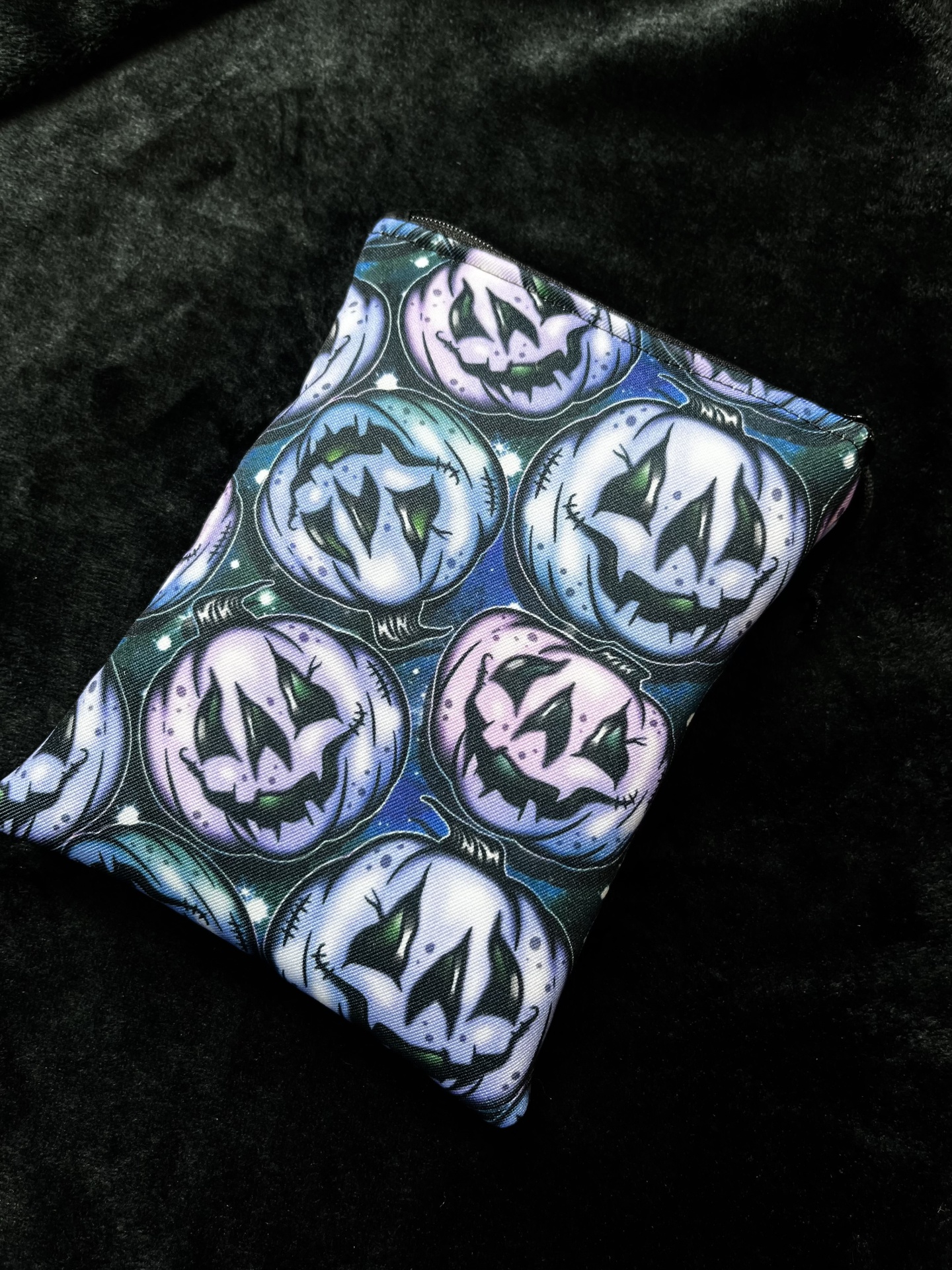 Pastel Pumpkins E-Reader Fabric with blue and purple jack-o-lantern pattern on black background
