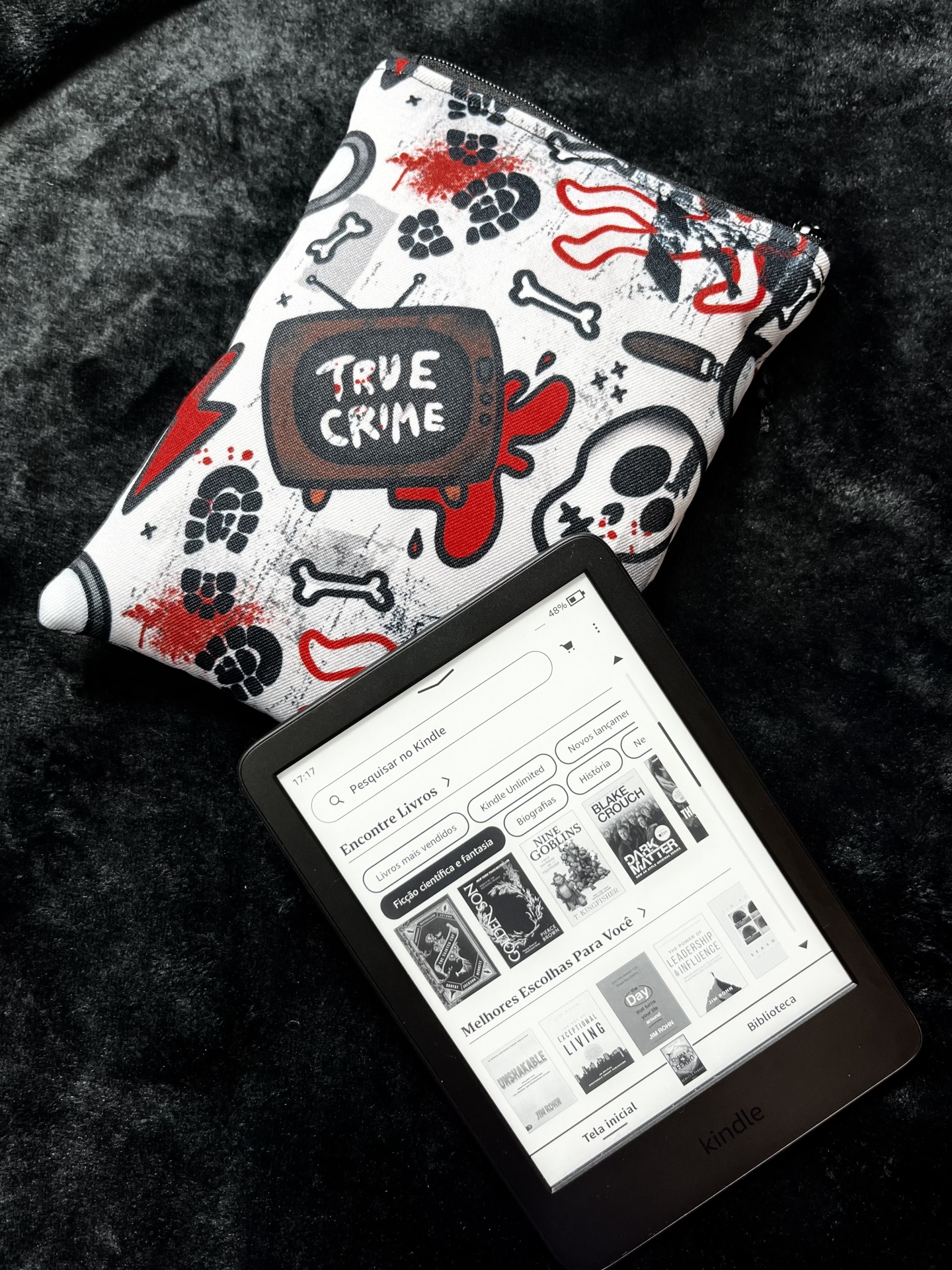 True Crime E-Reader Amazon Kindle e-reader with book store interface and a True Crime themed fabric pouch on black surface