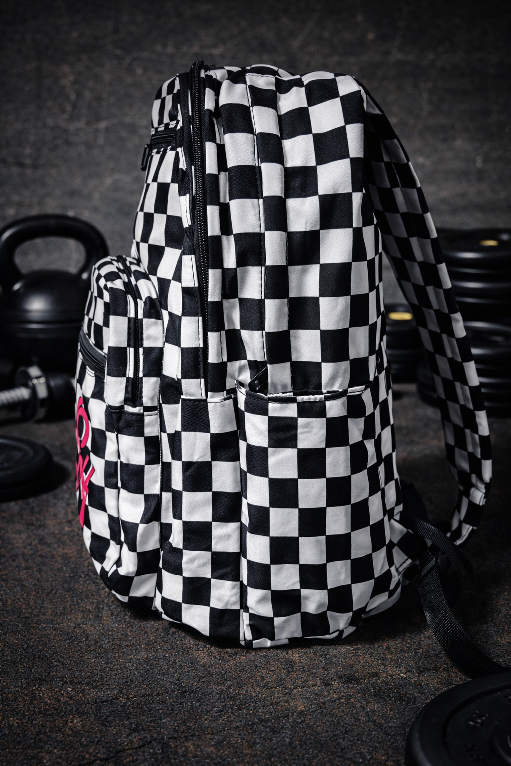 Gym Backpack - Pit Checker Black and white checkered backpack with zippers in a gym setting