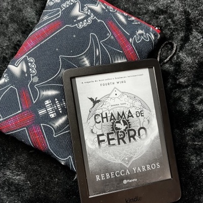 Kindle e-reader showing book cover, placed on guitar-patterned pouch and textured fabric.