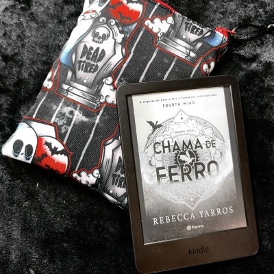 Kindle e-reader with book cover next to Halloween-themed fabric pouch