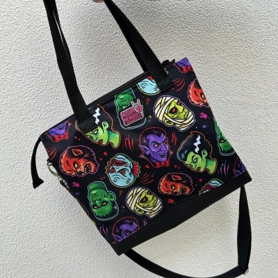 Black tote bag with colorful monster faces and MOSHPIT MEMORIES label