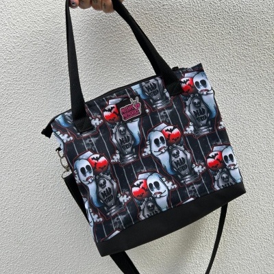 Black tote bag with spooky ghost and tombstone pattern held by tattooed hand