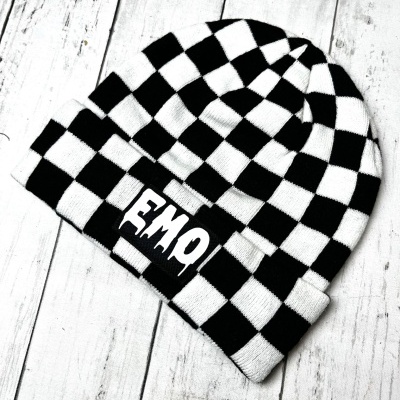 Black and white checkered knit beanie with EMO label on white wooden surface
