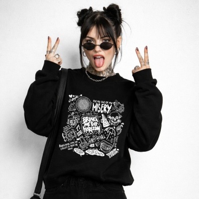 Black sweatshirt with white graffiti-style text and artwork worn by a woman with black hair in buns and sunglasses