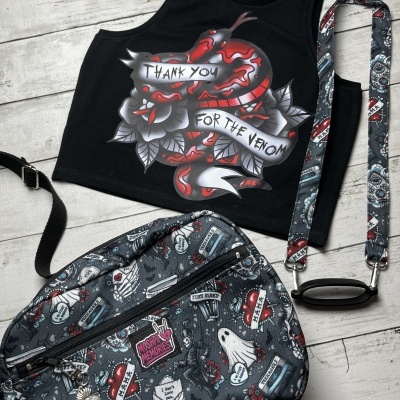 Black crop top with snake graphic and text next to a tattoo-style patterned messenger bag