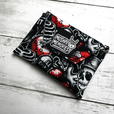 Carteira em tecido com padrão de caveiras e mãos em preto, branco e vermelho