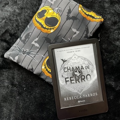 Kindle with book cover on fabric pouch with jack-o-lantern and bat design on black surface