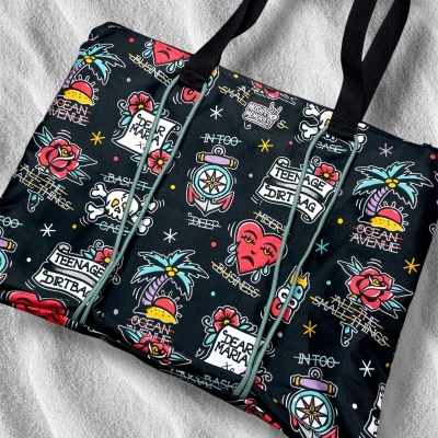 Tote bag with colorful tattoo-style designs and text on black fabric