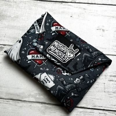 Black fabric clutch with rockabilly tattoo prints and MOSHPIT MEMORIES patch on white wooden background