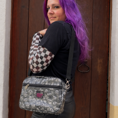 Woman with purple hair carrying gray skull print crossbody bag