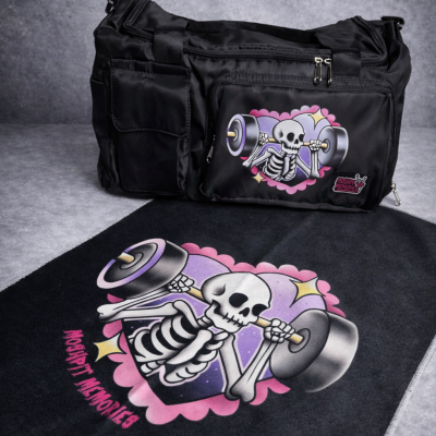 Black gym bag and black towel with cartoon skeleton lifting weights design