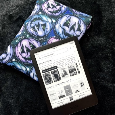 Kindle e-reader and a fabric pouch with jack-o-lantern pattern on a black surface