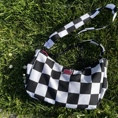 Black and white checkered handbag on grass with MOSHPIT MEMORIES label