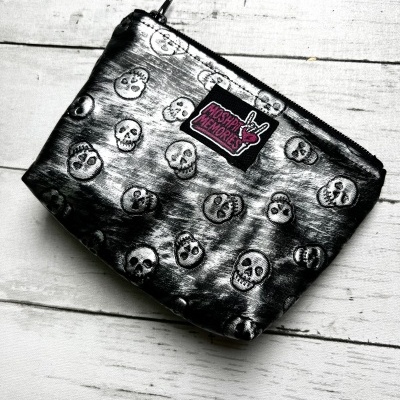 Black pouch with skull pattern and MOSHIPI MEMORIES label on white wood
