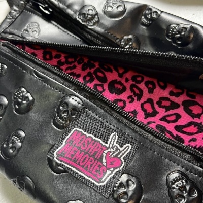 Black skull embossed faux leather bag with pink leopard print interior and MOSHPIT MEMORIES patch.