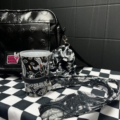 Black skull-embossed bag, Harley Davidson cup, and matching black and white fabric strap and scrunchie on checkered tablecloth