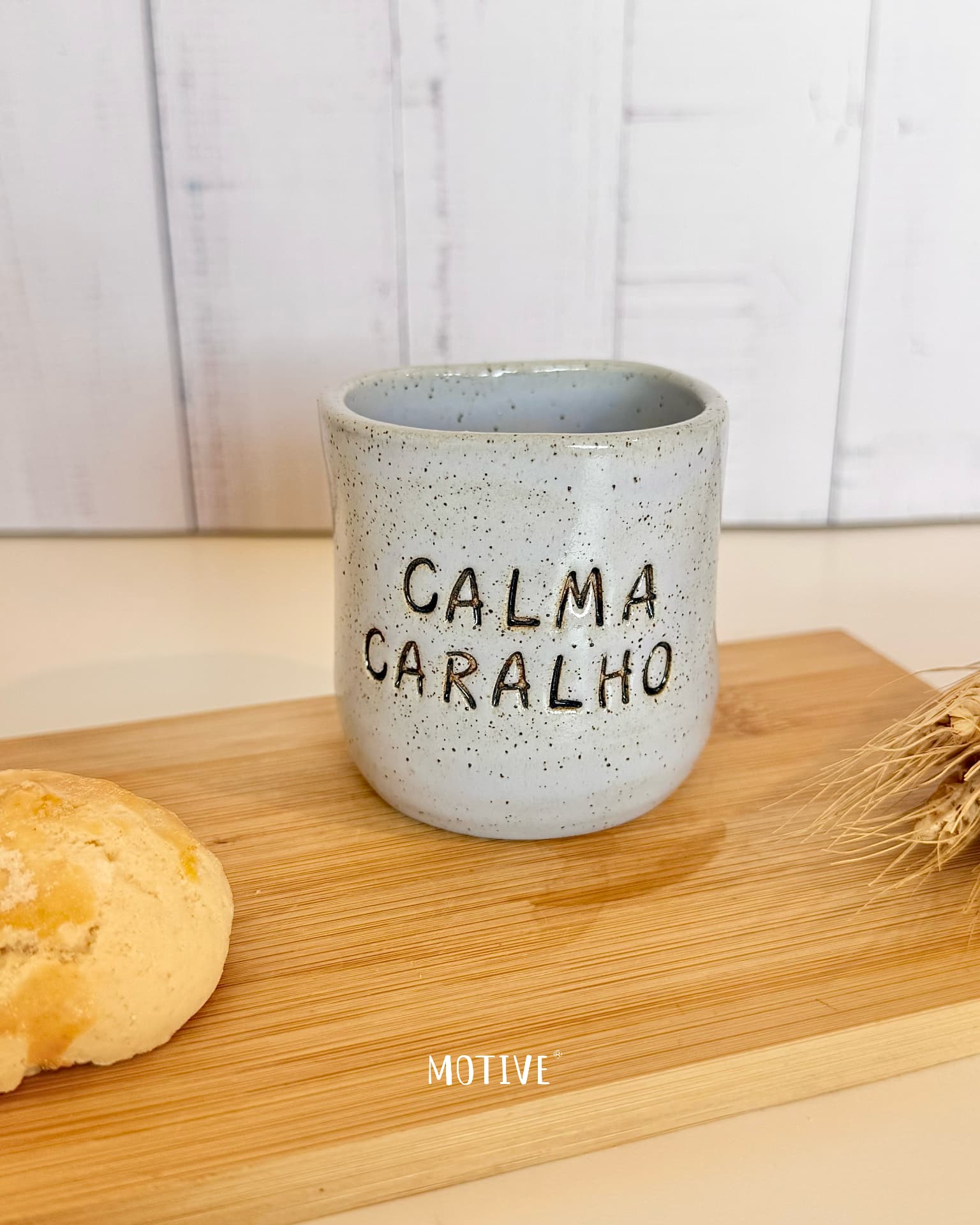 Copinho de Café CALMA CARALHO - Azul Celeste Caneca de cerâmica cinza com texto CALMA CARALHO sobre tábua de madeira com pão e espigas de trigo