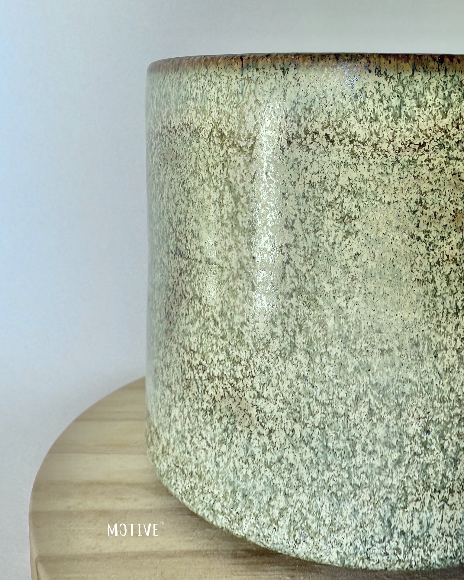 Caneca Sábios Dizem Foda-se Vaso cerâmico verde com textura granulada na superfície, em cima de uma mesa de madeira.