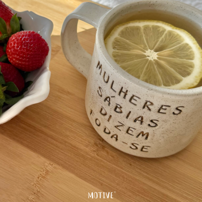 Caneca branca de cerâmica com texto e chá com limão ao lado de morangos
