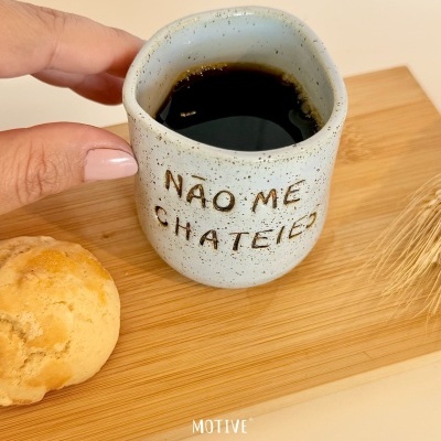 Caneca de cerâmica branca com texto gravado e café preto em tábua de madeira