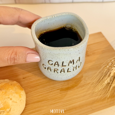 Caneca de cerâmica com café preto sobre tábua de madeira