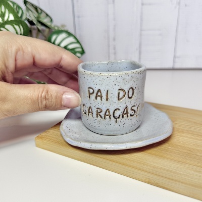 Xícara de cerâmica cinza com texto e base de madeira