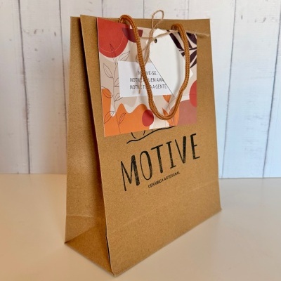 Saco de papel castanho com etiqueta decorativa colorida e alças de corda