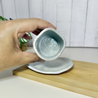 Conjunto de cerâmica azul claro e branco com salpicos castanhos numa base de madeira