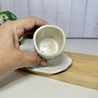 Mão segurando chávena de cerâmica bege com padrão