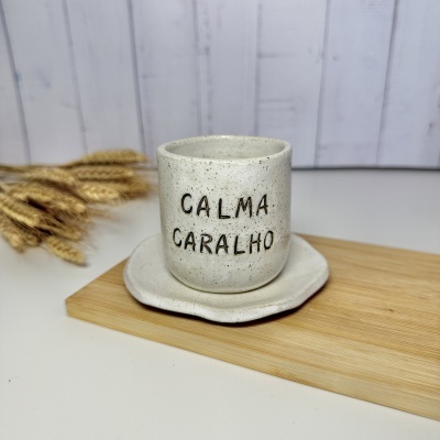Caneca de cerâmica castanha clara com texto CALMA CARALHO.