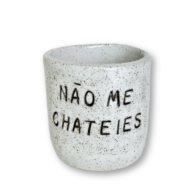 Copo de cerâmica branco com manchas pretas e texto gravado