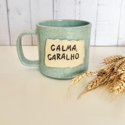 Caneca verde água com texto CALMA, CARALHO em etiqueta bege