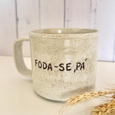 Caneca de cerâmica bege com manchas castanhas e texto FODA-SE, PA em preto