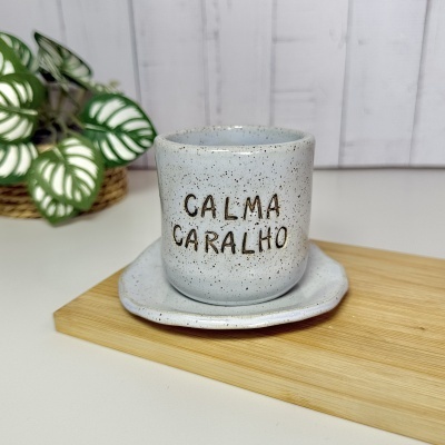Caneca cinza com manchas pretas e texto CALMA CARALHO