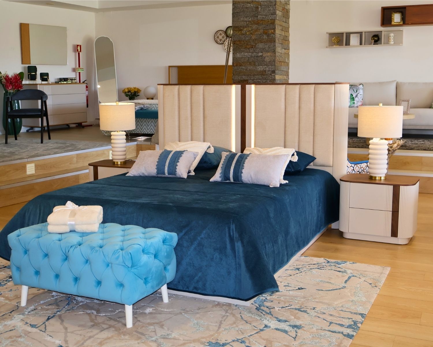 Cama de casal GYO com cabeceira estofada e iluminação Quarto com cama azul e cabeceira bege com mesinhas de cabeceira e banco azul turquesa