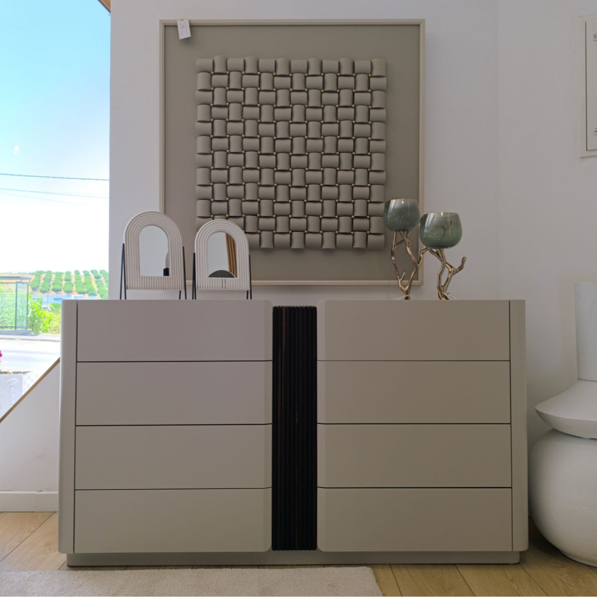 Cómoda DUNE em lacado mate Cômoda cinza claro com gavetas, vasos verdes, esculturas brancas e quadro cinza na parede
