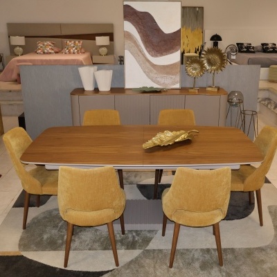 Mesa de jantar de madeira com seis cadeiras amarelas e aparador cinza ao fundo