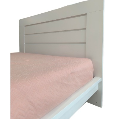 Cabeceira de cama branca com lençol rosa claro com padrão