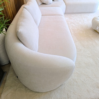 Sofá branco off-white arredondado com almofadas grandes e carpete bege clara