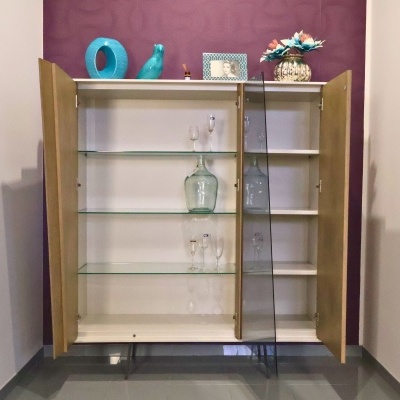 Móvel armário aberto com prateleiras de vidro e objetos decorativos no topo