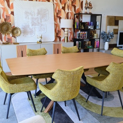 Mesa de jantar retangular em madeira clara com seis cadeiras amarelas sobre tapete colorido em sala decorada